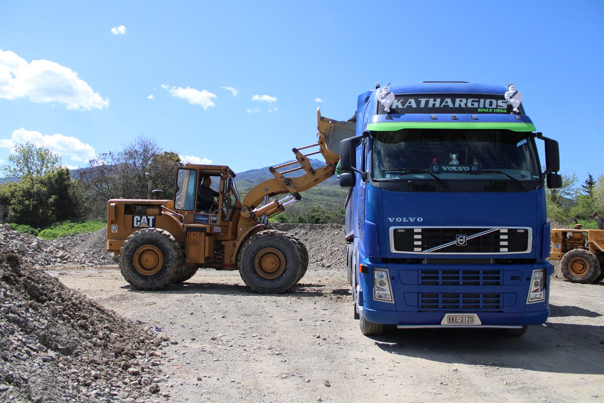Φορτωτής CAT φορτώνει το μπλε φορτηγό της Kathargios Group με αδρανή υλικά